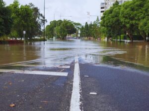 Flooded road with caution signs and traffic cones in Queensland, highlighting the importance of flood safety.